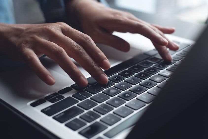 Közelkép üzletasszony kezéről, aki laptopon gépel.