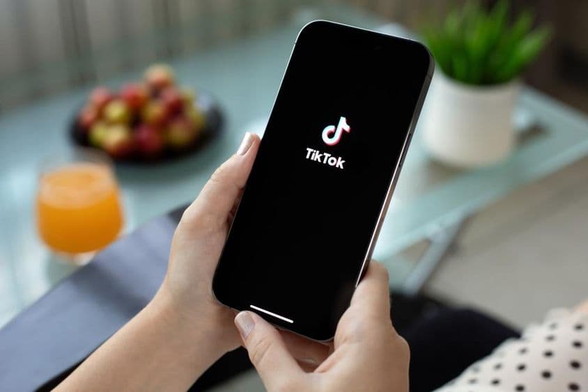 Nő kezében Apple iPhone TikTok a képernyőn.
