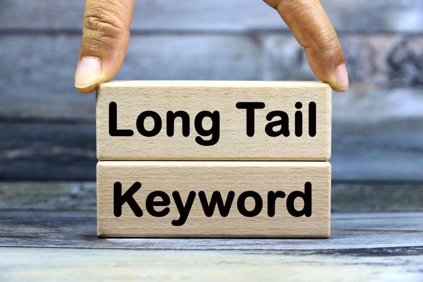 Long Tail kulcsszó rövid szó angol betű szöveggel egy fa blokkon.