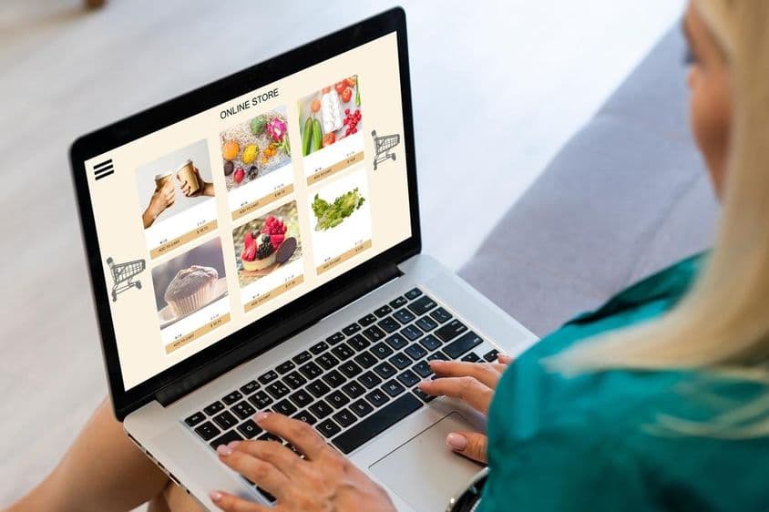 Nő ül és online rendel ételt egy laptopon.