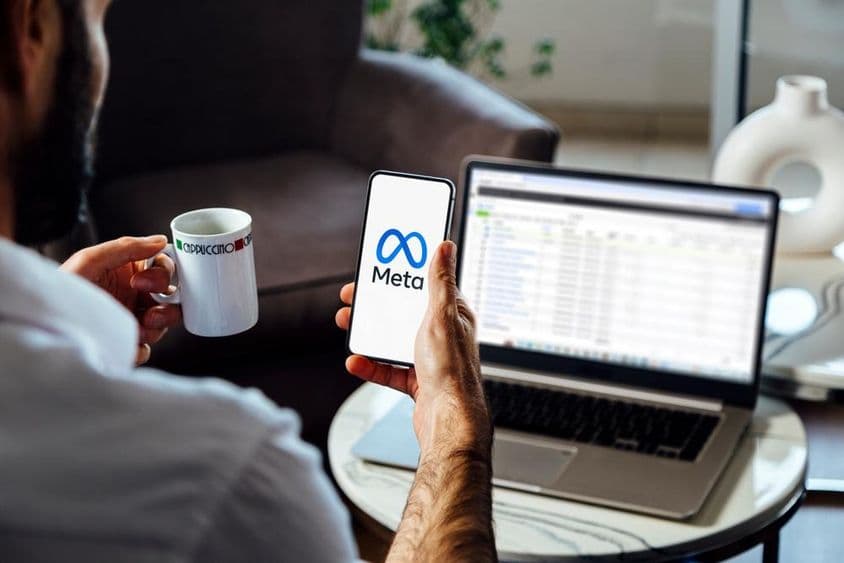 Férfi egy okostelefont tart a kezében, a mobiltelefon képernyőjén a Meta logó látható.