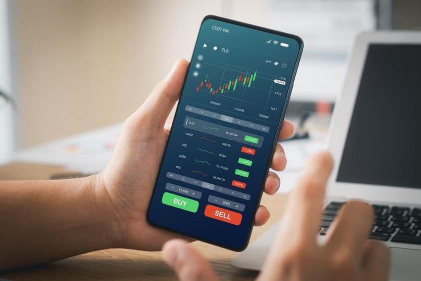 Üzletemberek tőzsdei befektetésekkel dolgoznak, okostelefon app.
