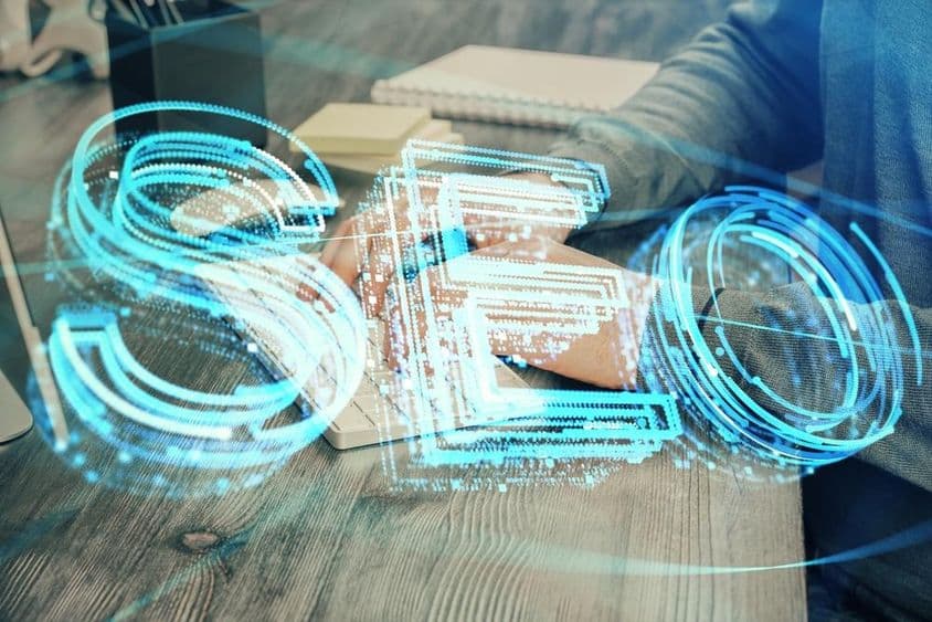 Dupla expozíció SEO ikonnal, háttérben számítógépen dolgozó férfival.