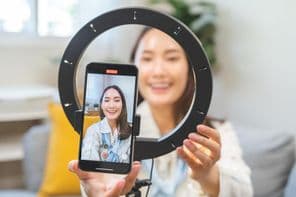 Egy fiatal nő blogger beállítása okostelefonnal.