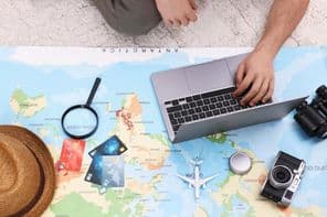 Utazási blogger laptoppal és térképpel tervezi meg az utazást.