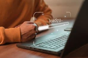 Férfi laptopot használ szoftver letöltéséhez és üzleti weboldal betöltésére vár.