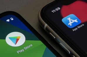 Google Play Áruház és az Apple App Store ikonjai rendre egy-egy okostelefonon.