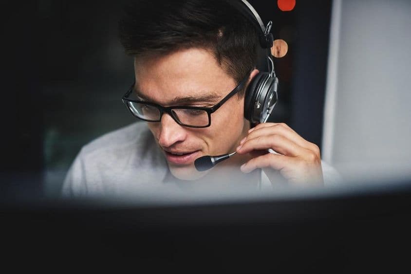 Call center, ember és számítógép fejhallgatóval ügyfélszolgálati kommunikációhoz és GYIK támogatáshoz.