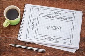 Weboldal elrendezésének tervezése - vázlat spirálfüzetben egy csésze kávéval.