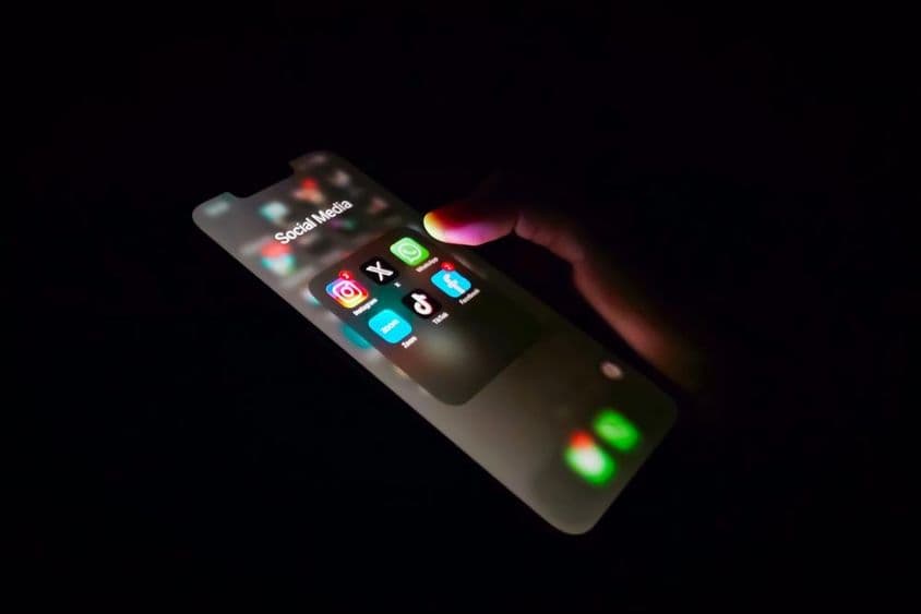 A közösségi média alkalmazások használata az okostelefonon a sötétben.