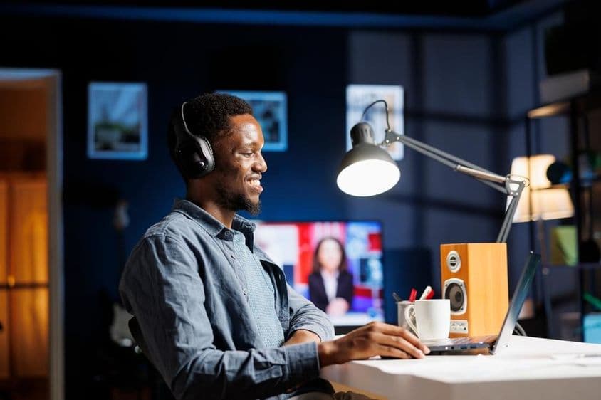 Egy alkalmazott otthon podcastot hallgat és egy új terven dolgozik.