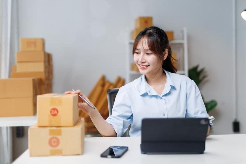 Mosolygó fiatal nő pakolja az árút.